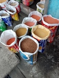 Bulk sacks filled with various millets like bajra, ragi, and jowar stacked in a warehouse.