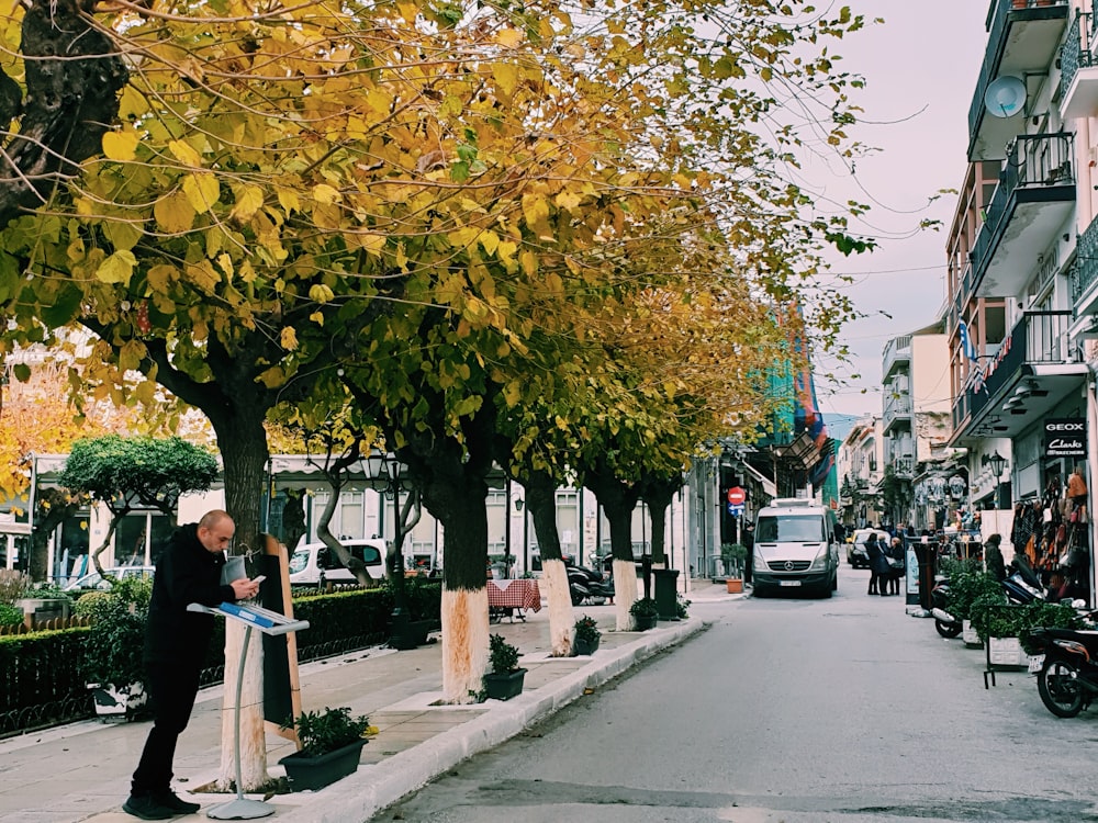 a man standing on the side of a road next to a tree