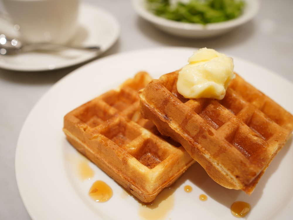 a white plate topped with two waffles covered in butter