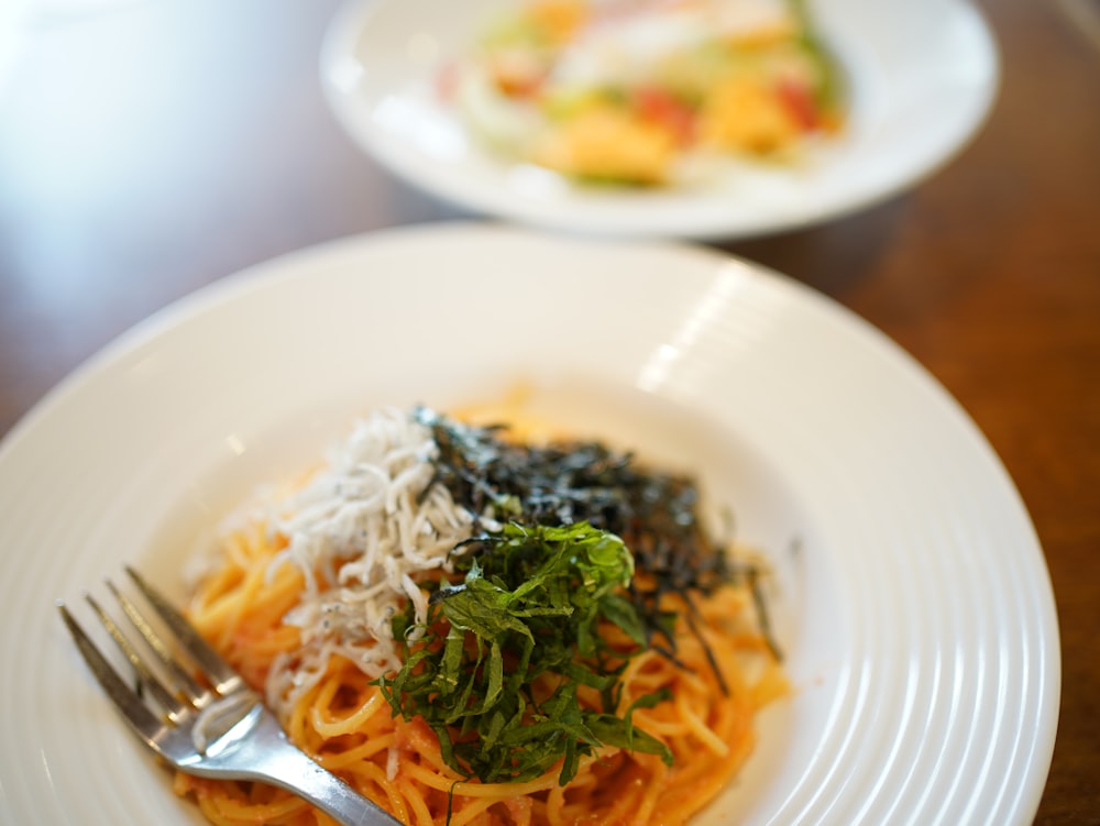 a white plate topped with pasta and greens