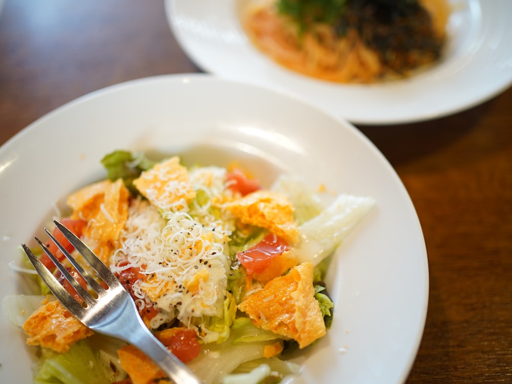 a white plate topped with a salad and a fork