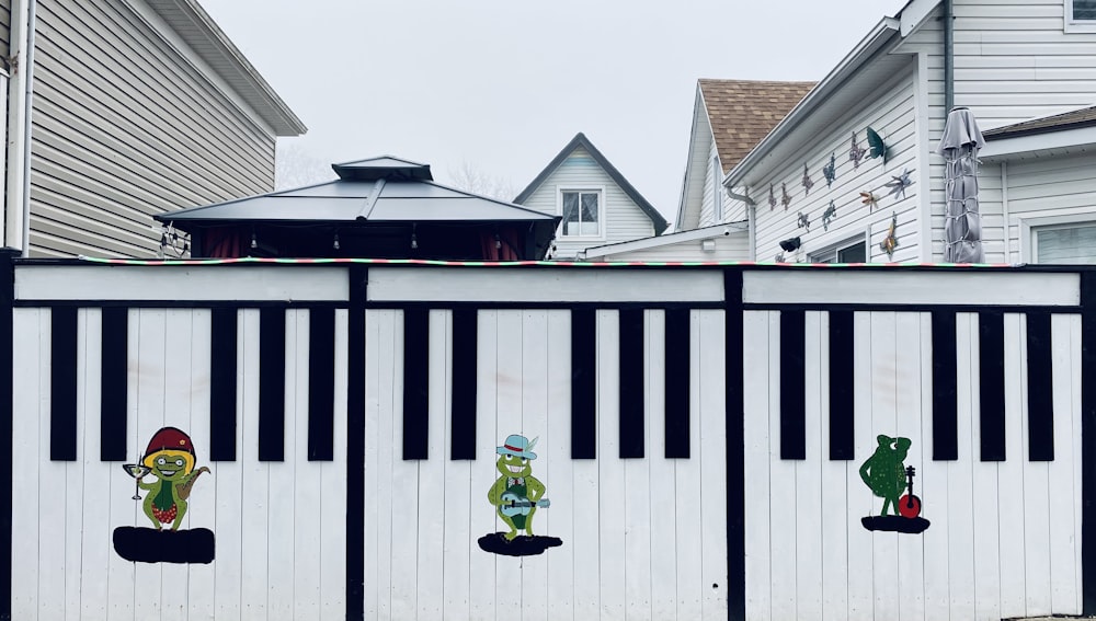 a white fence with black and white stripes and cartoon characters painted on it