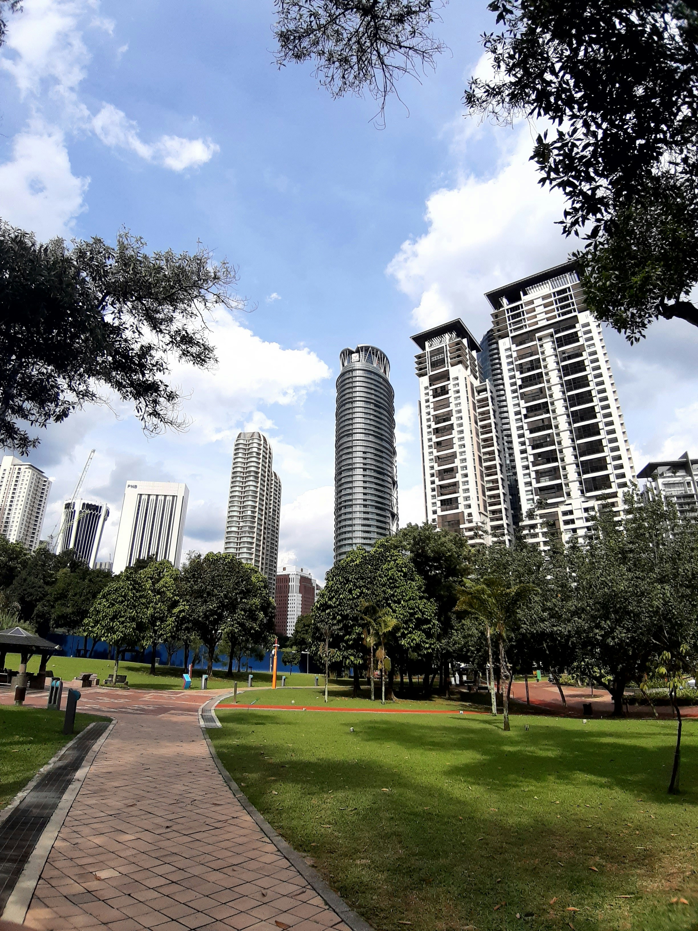 a walkway in a park with tall buildings in the background