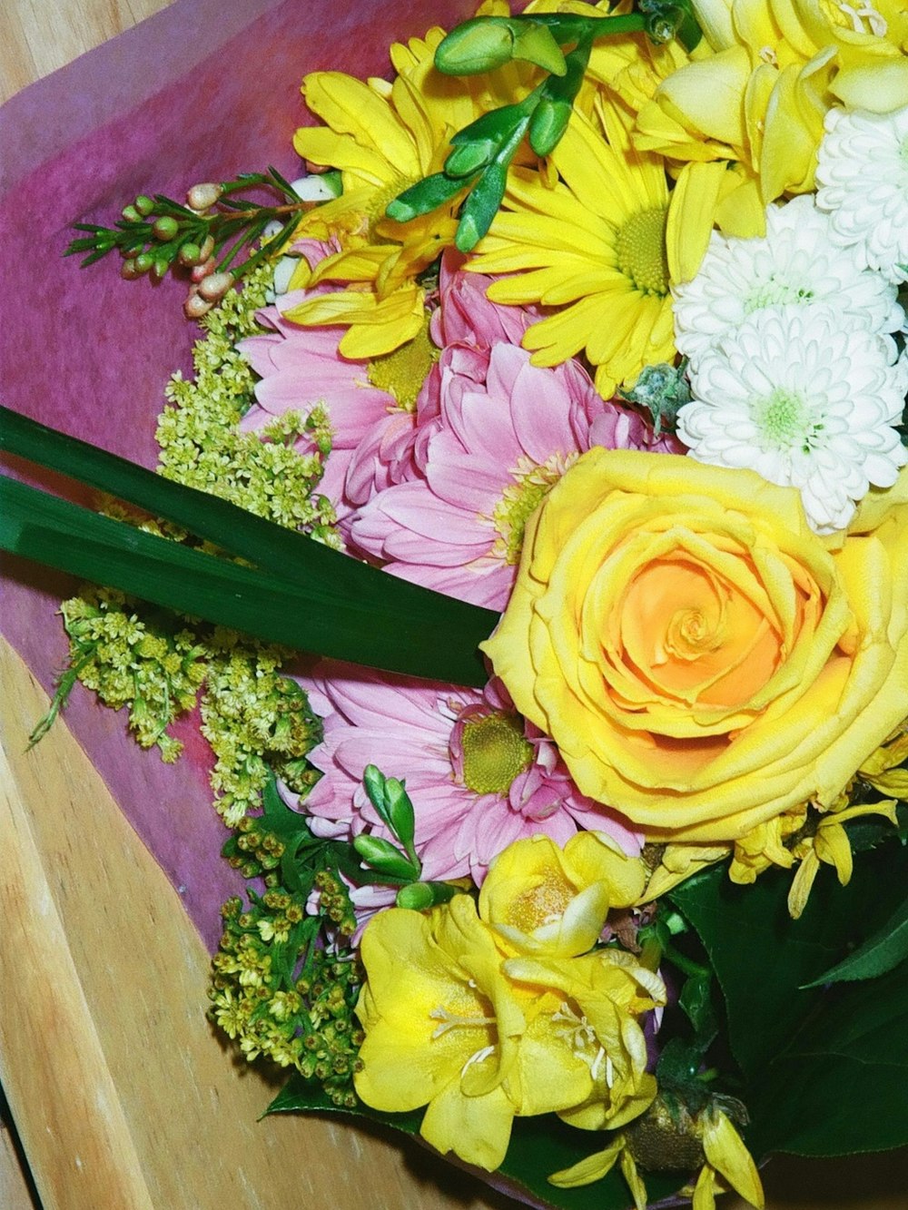 ein Strauß gelber und rosa Blumen auf einem Tisch
