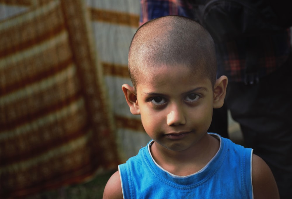 a young boy with a bald head and blue shirt