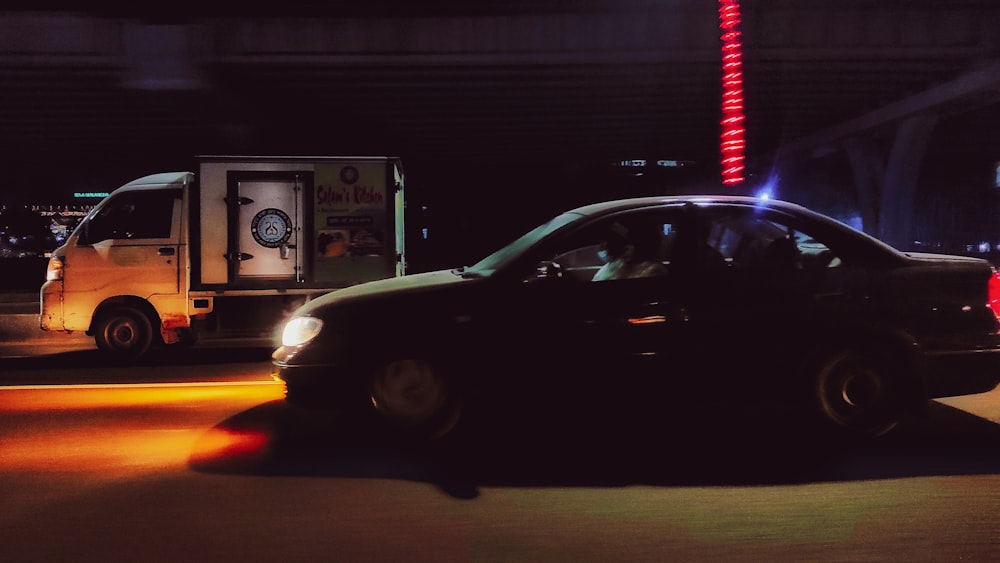 a black car driving down a street at night