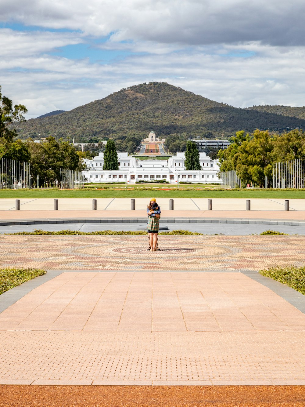 Una persona in piedi di fronte a una fontana con una montagna sullo sfondo