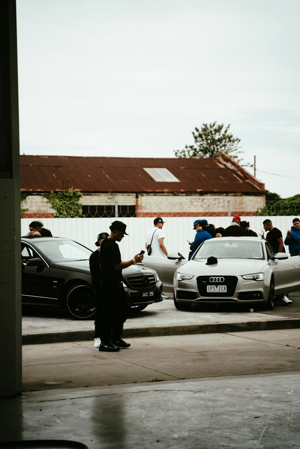 a group of people standing around parked cars