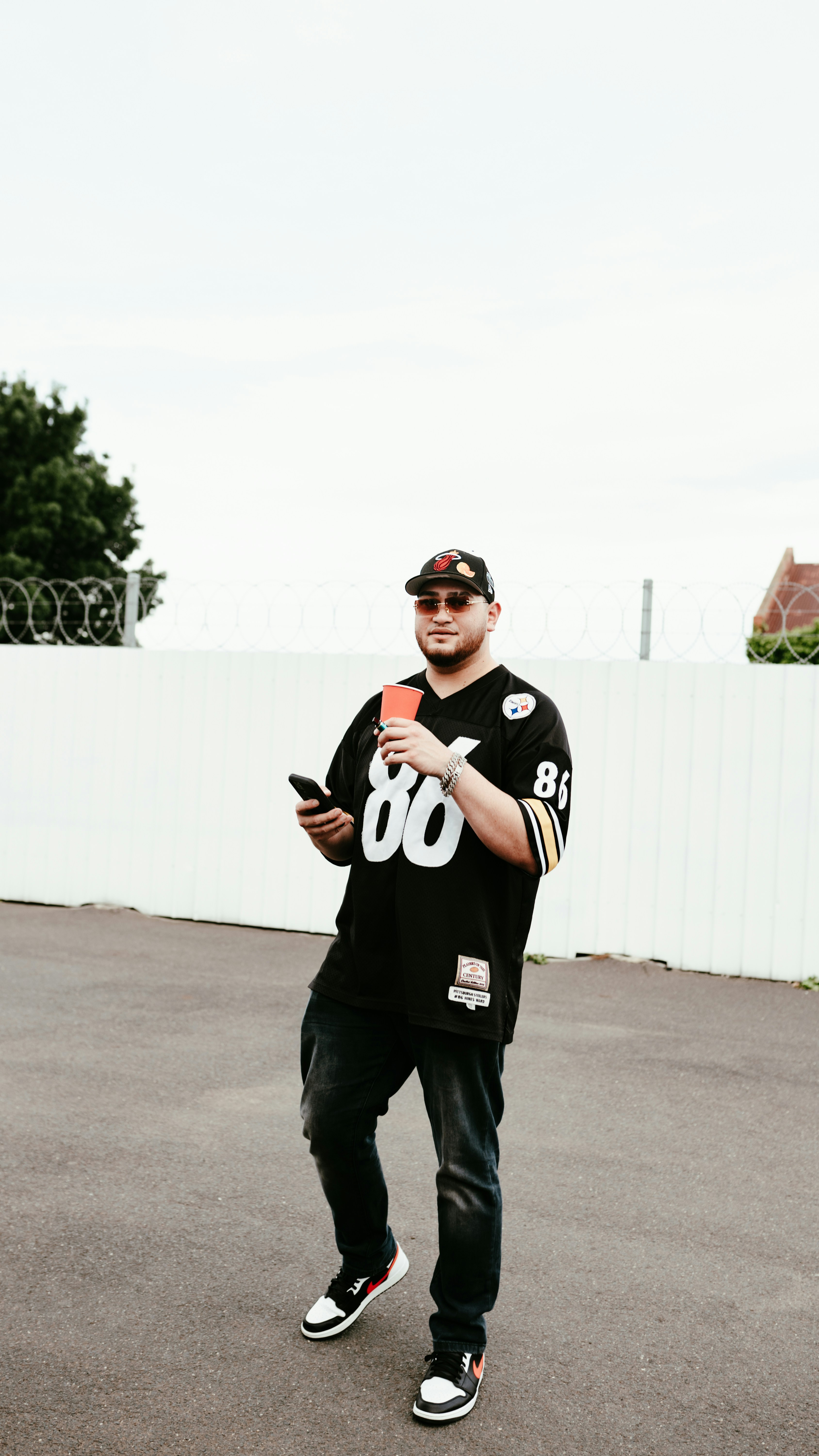 a man standing in a parking lot holding a cell phone