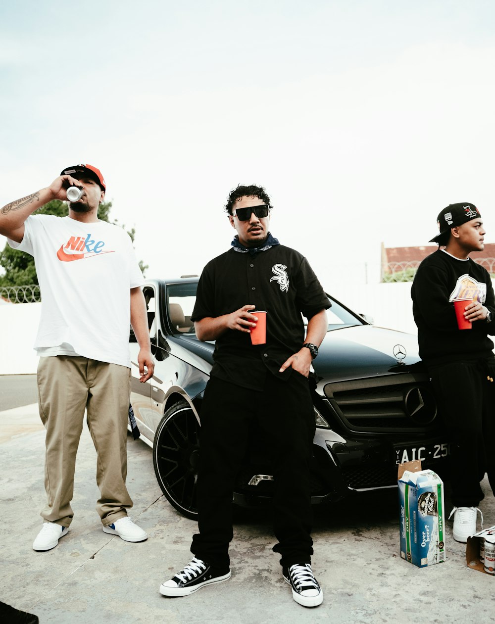 a group of men standing next to a car