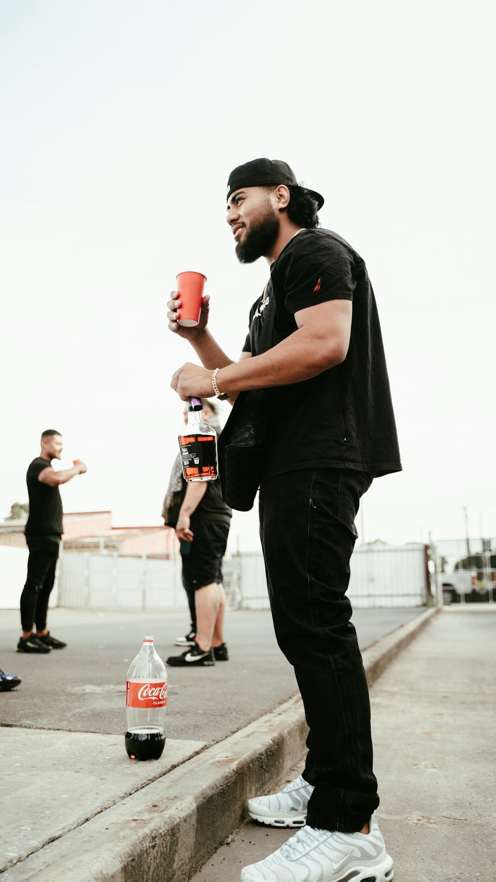 a man holding a cup of coffee while standing on a sidewalk