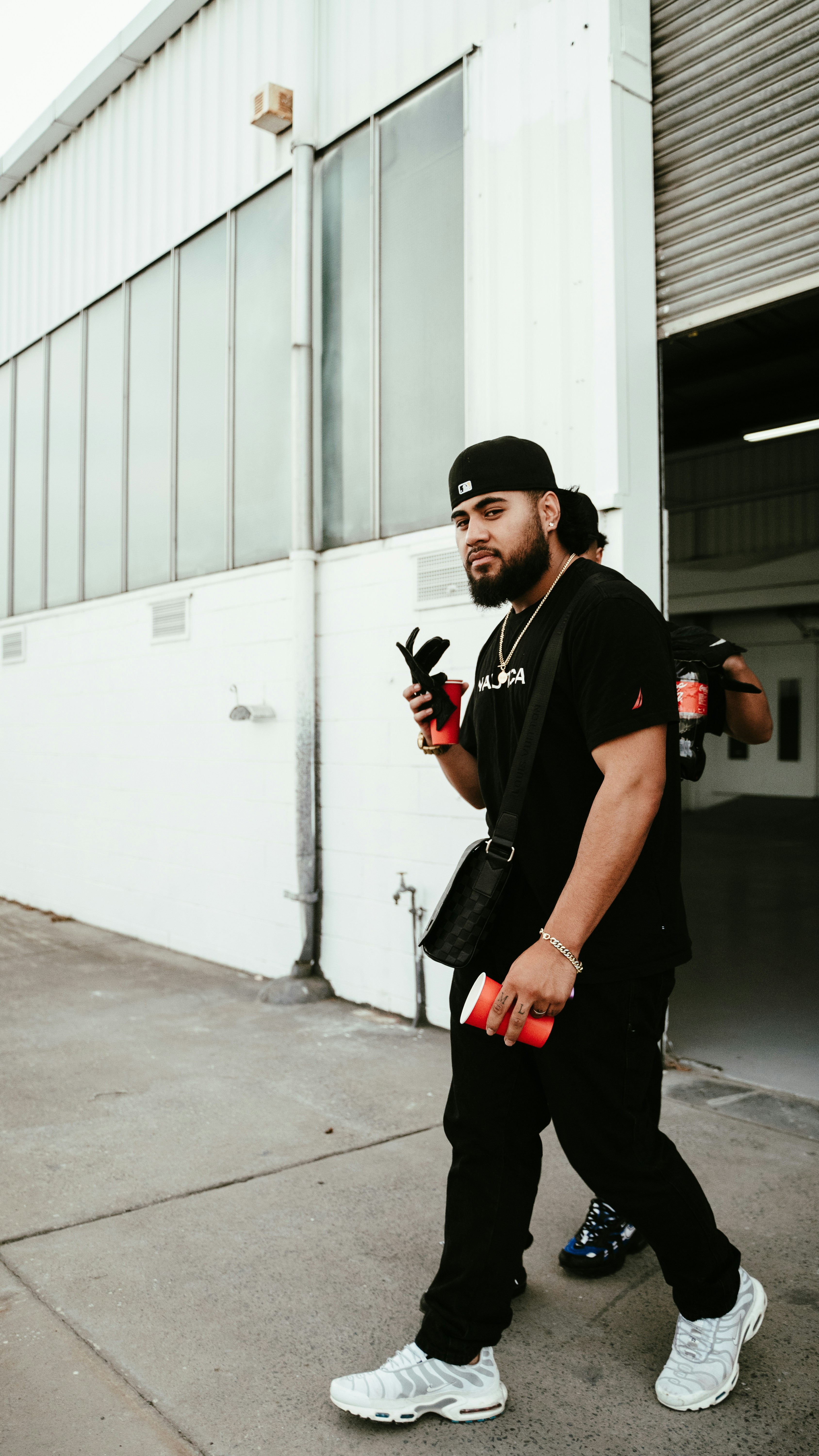 a man walking down a street holding a pair of orange dumbs
