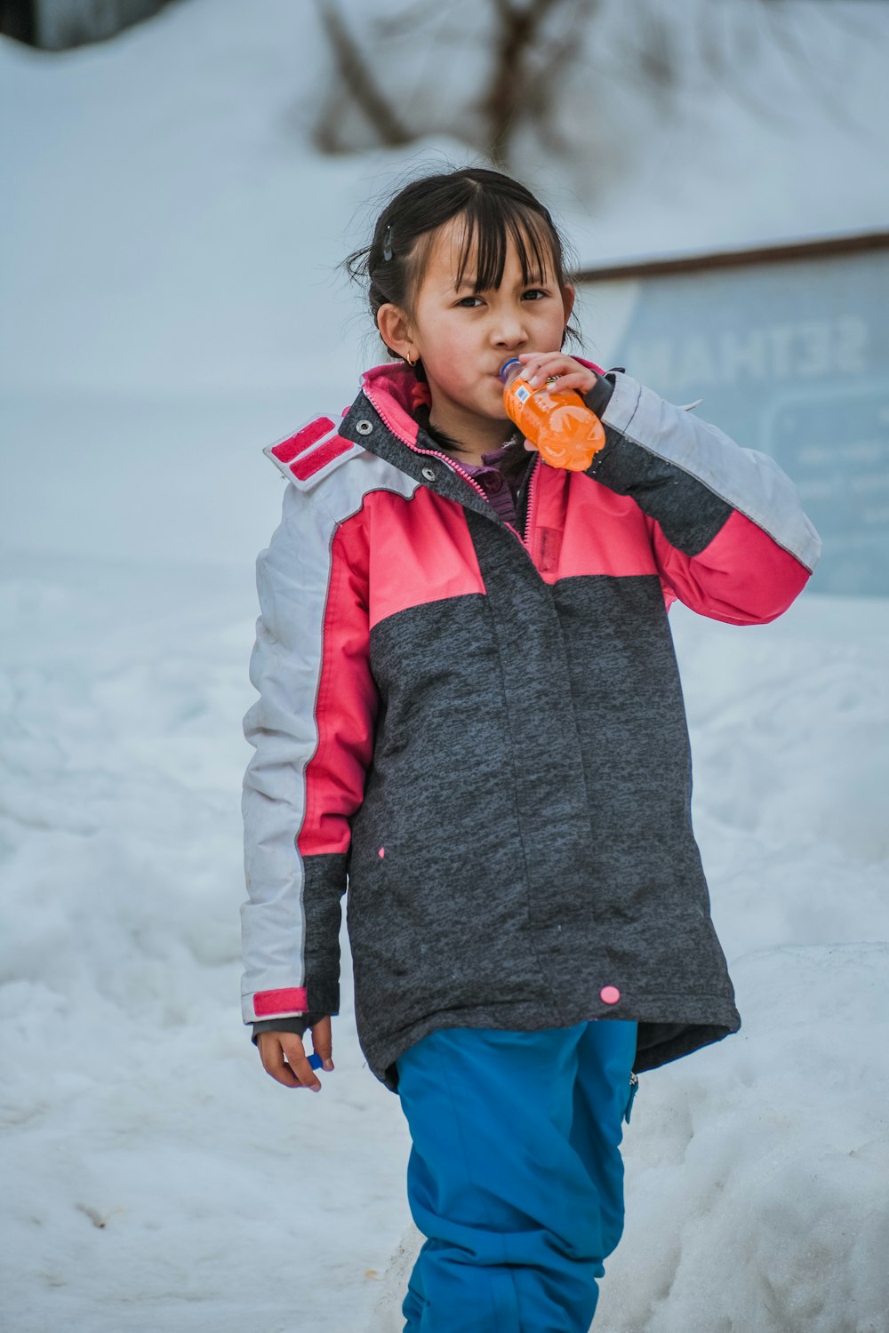 a little girl standing in the snow eating something