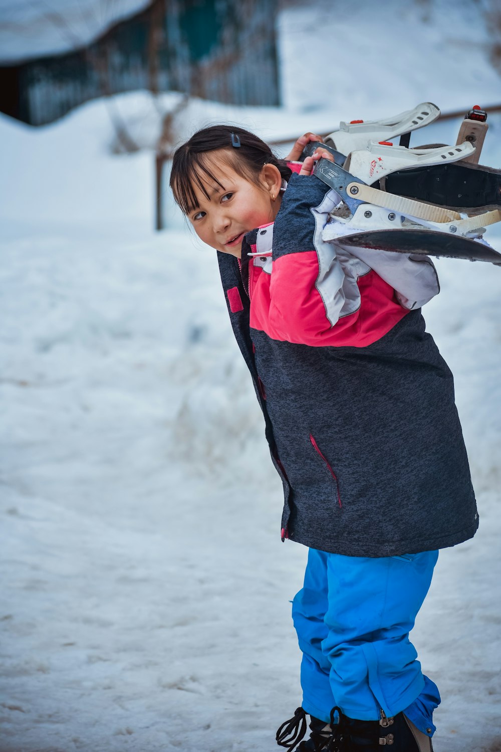 uma criança pequena segurando uma prancha de snowboard em cima de um chão coberto de neve