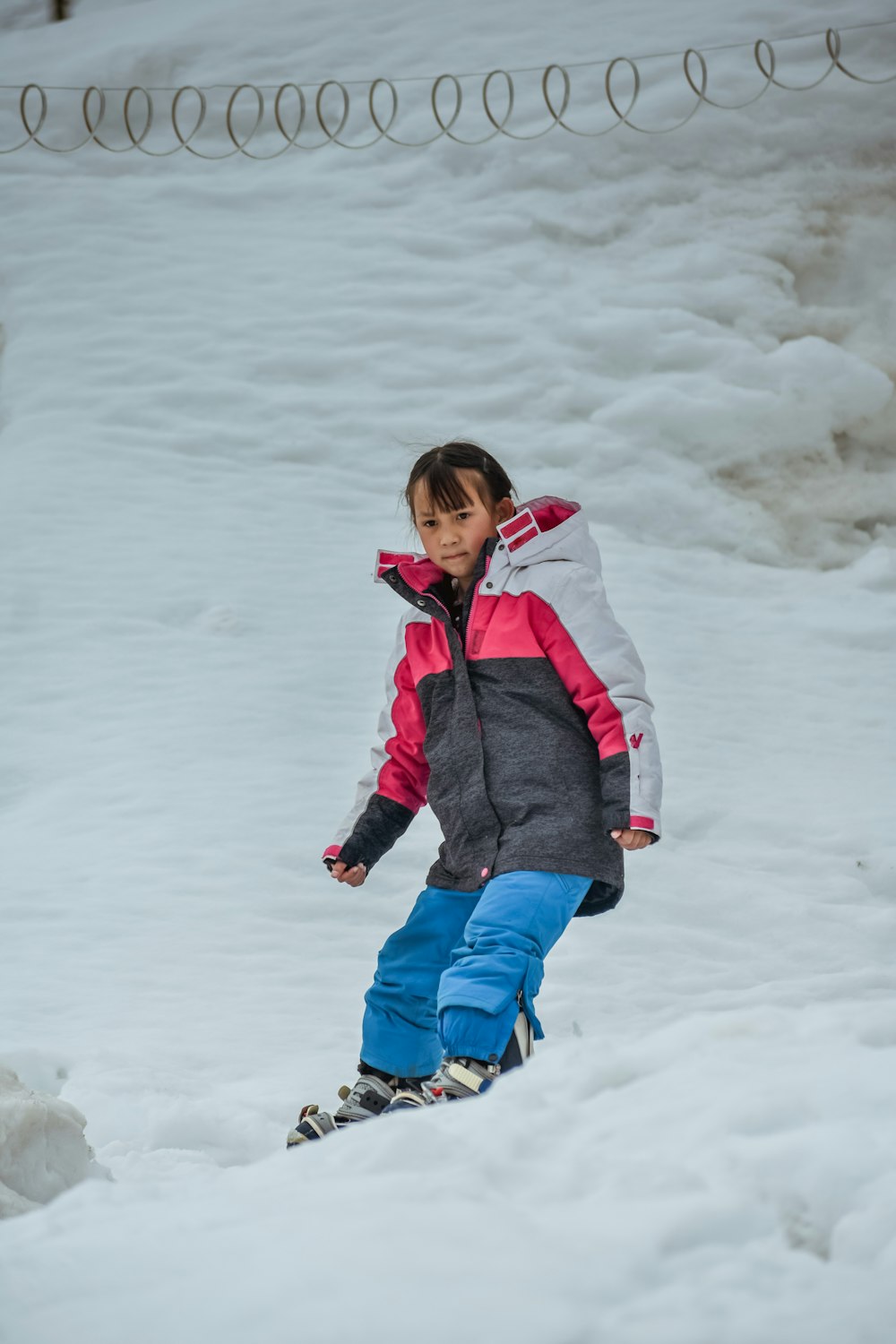 a young girl riding a snowboard down a snow covered slope