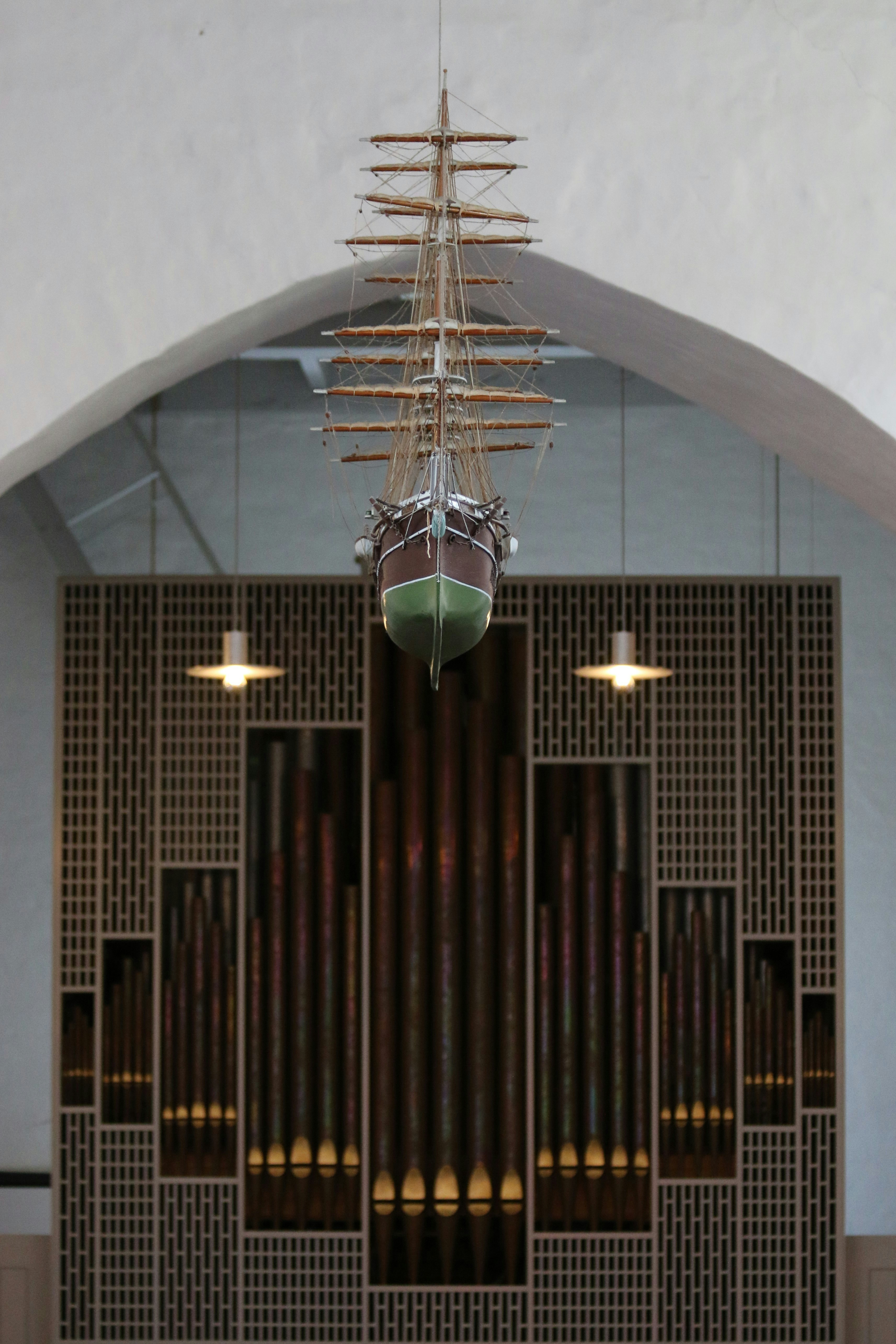 A pipe organ in a church with a boat hanging from the ceiling photo