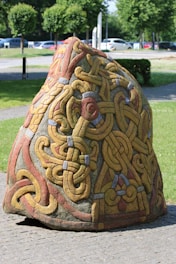 a rock with a design on it sitting on a sidewalk