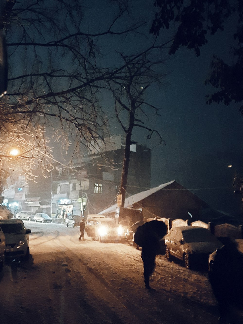 a person walking down a snow covered street at night