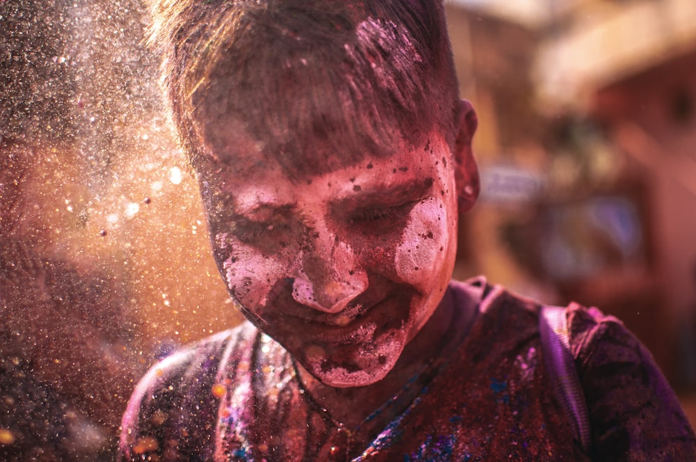 a young boy covered in colored powder and sprinkles