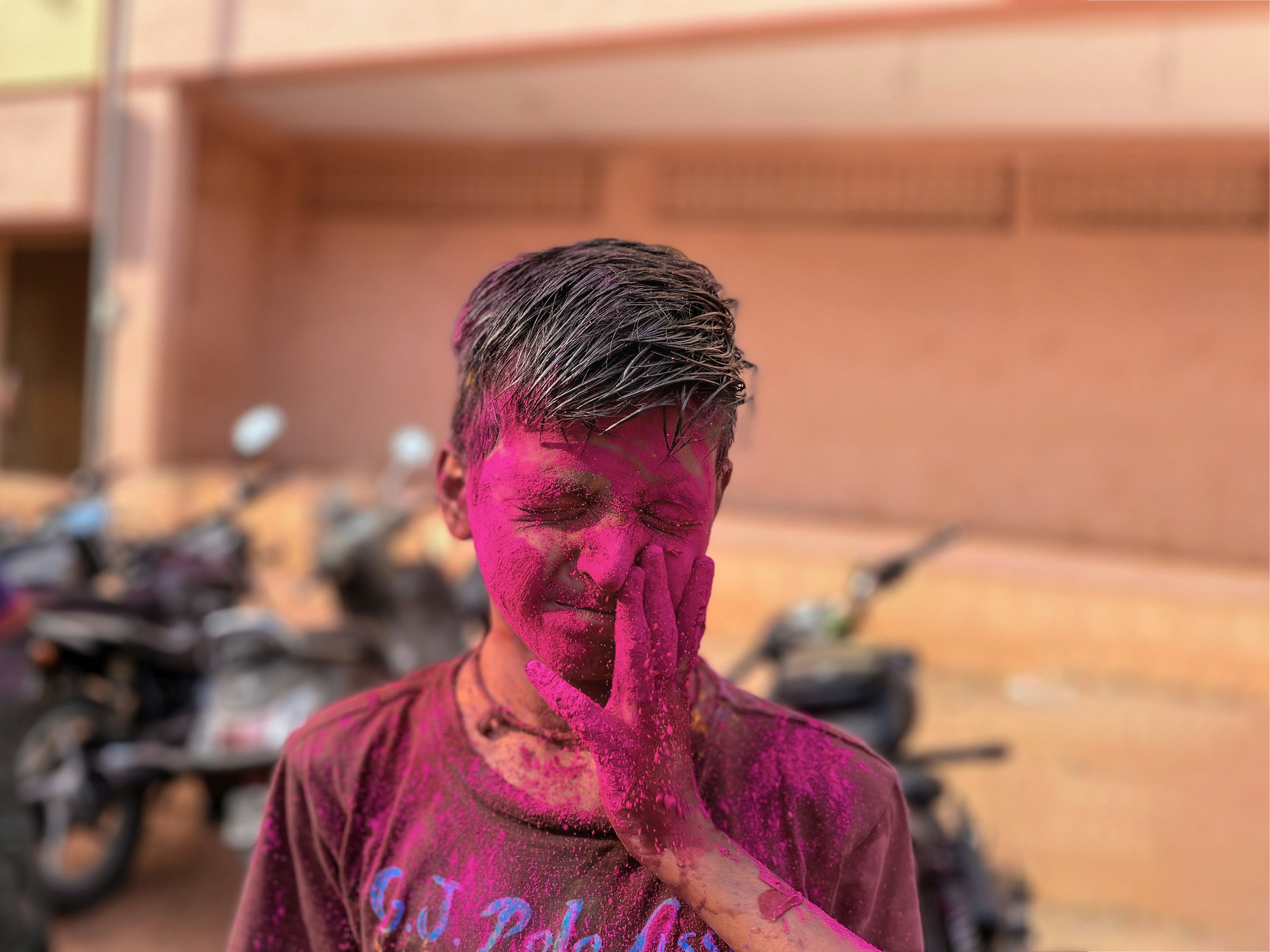 a man covered in pink paint standing in front of a motorcycle