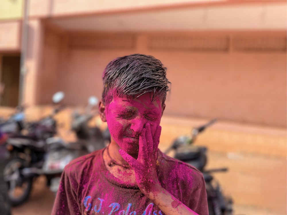 a man covered in pink paint standing in front of a motorcycle