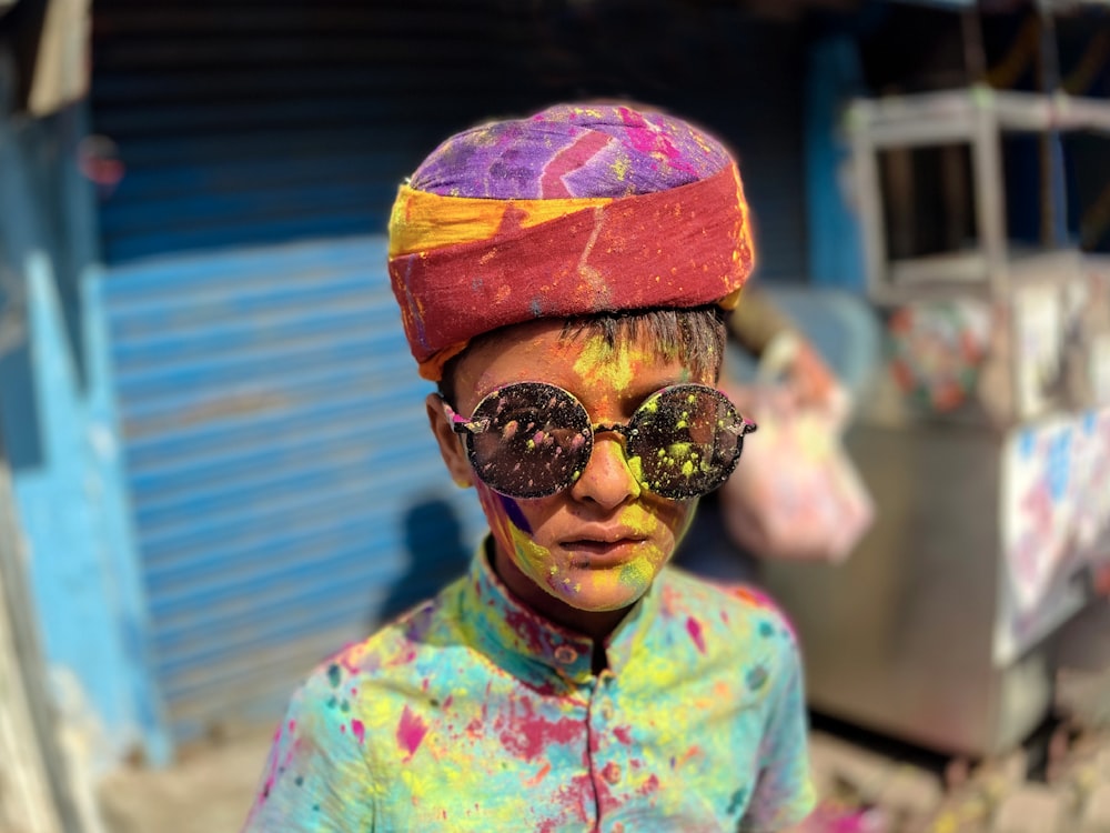 a young boy wearing sunglasses and a colorful hat