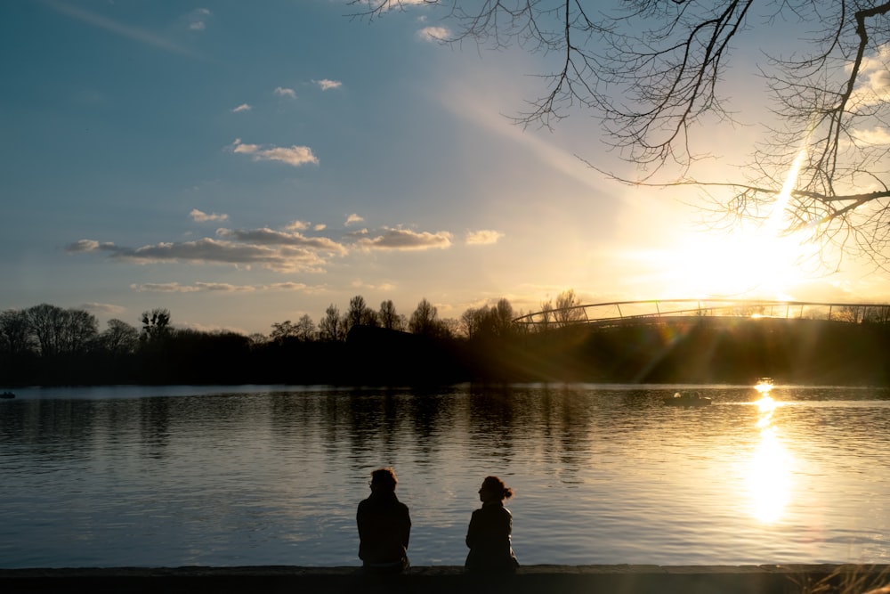 a couple of people sitting on a bench near a body of water
