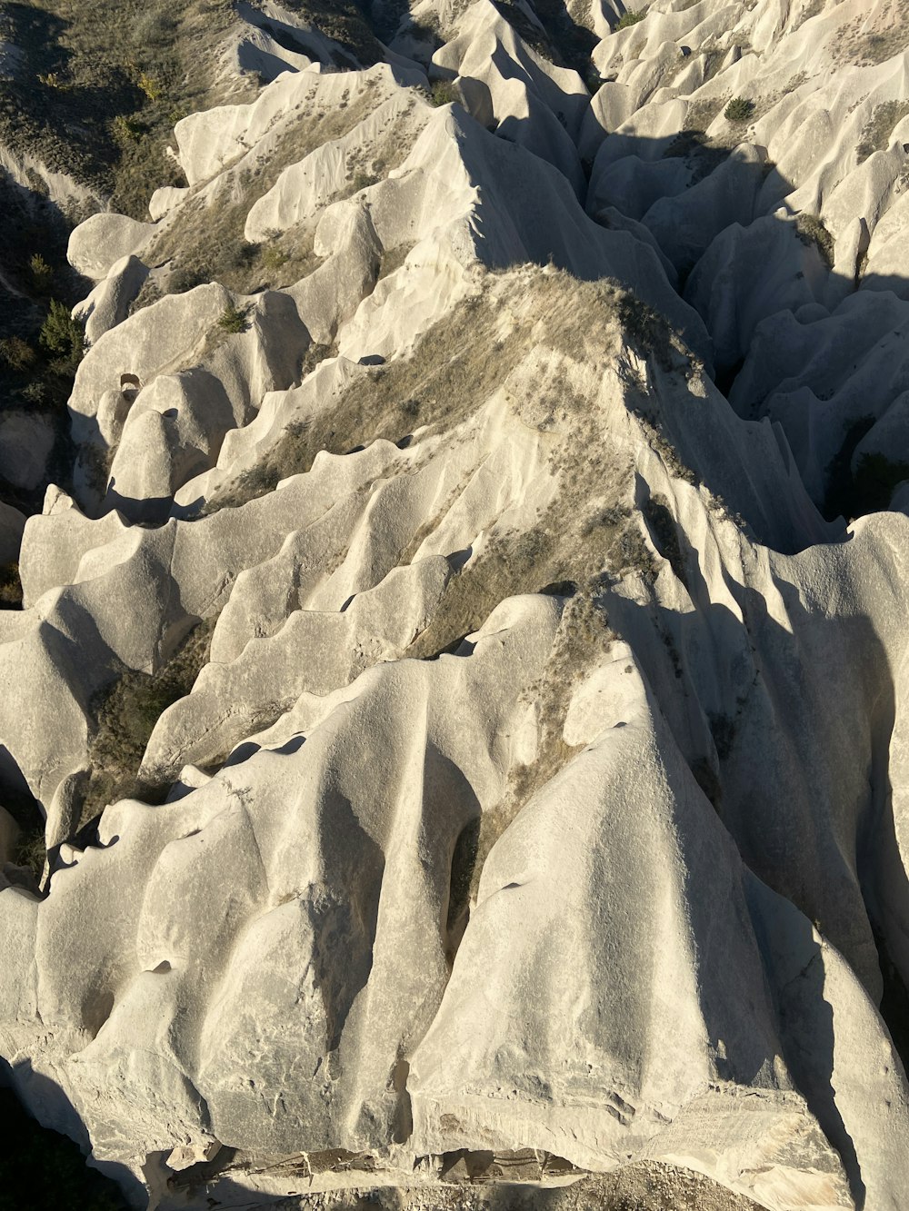 a view of a mountain range with rocks and grass in the foreground