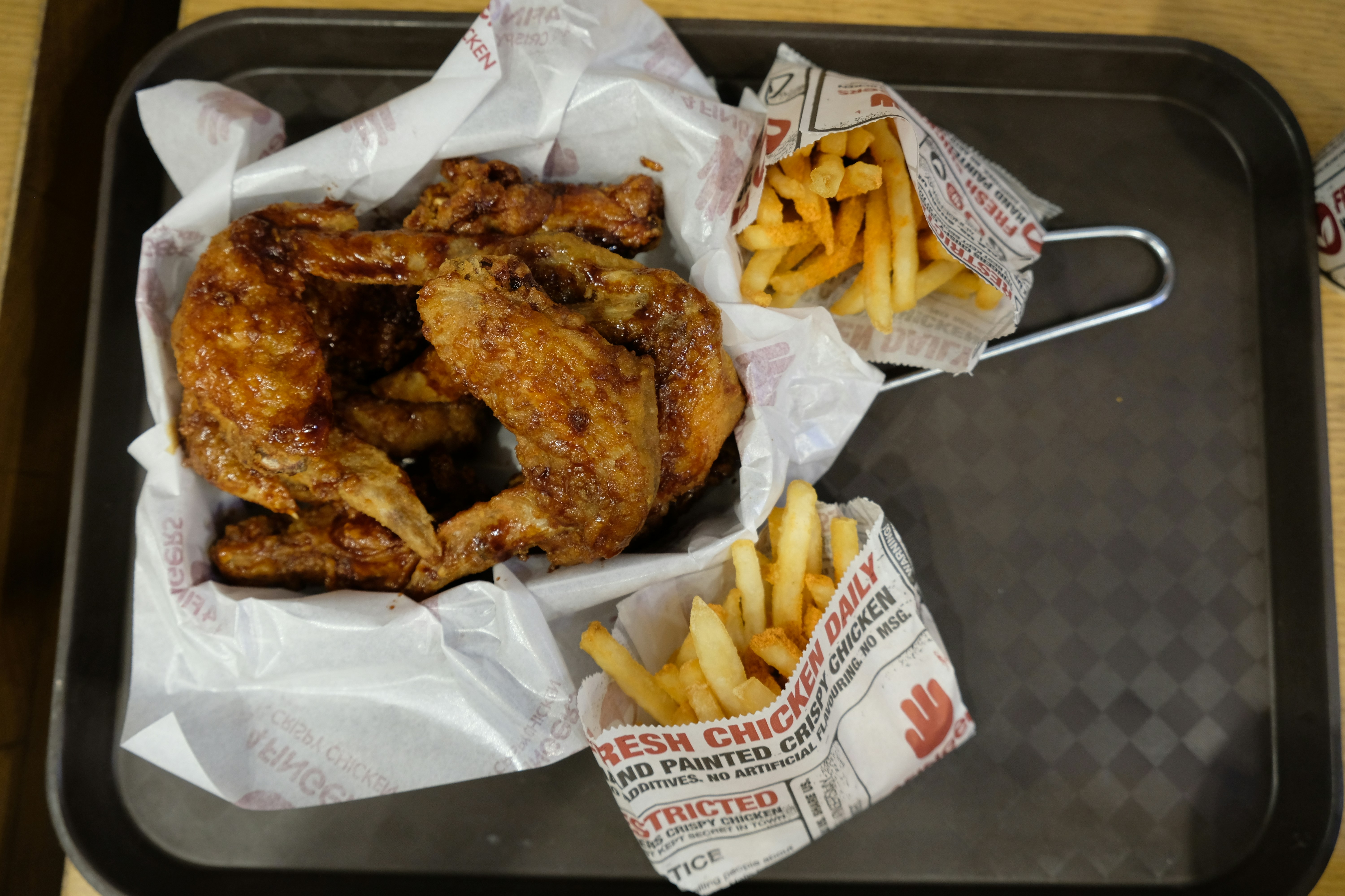 a tray with chicken wings and french fries