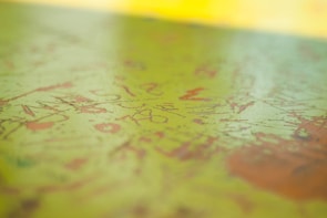 A detailed close-up of a textured canvas showing layers of yellow and emerald green.