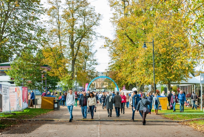 a group of people walking down a street next to trees