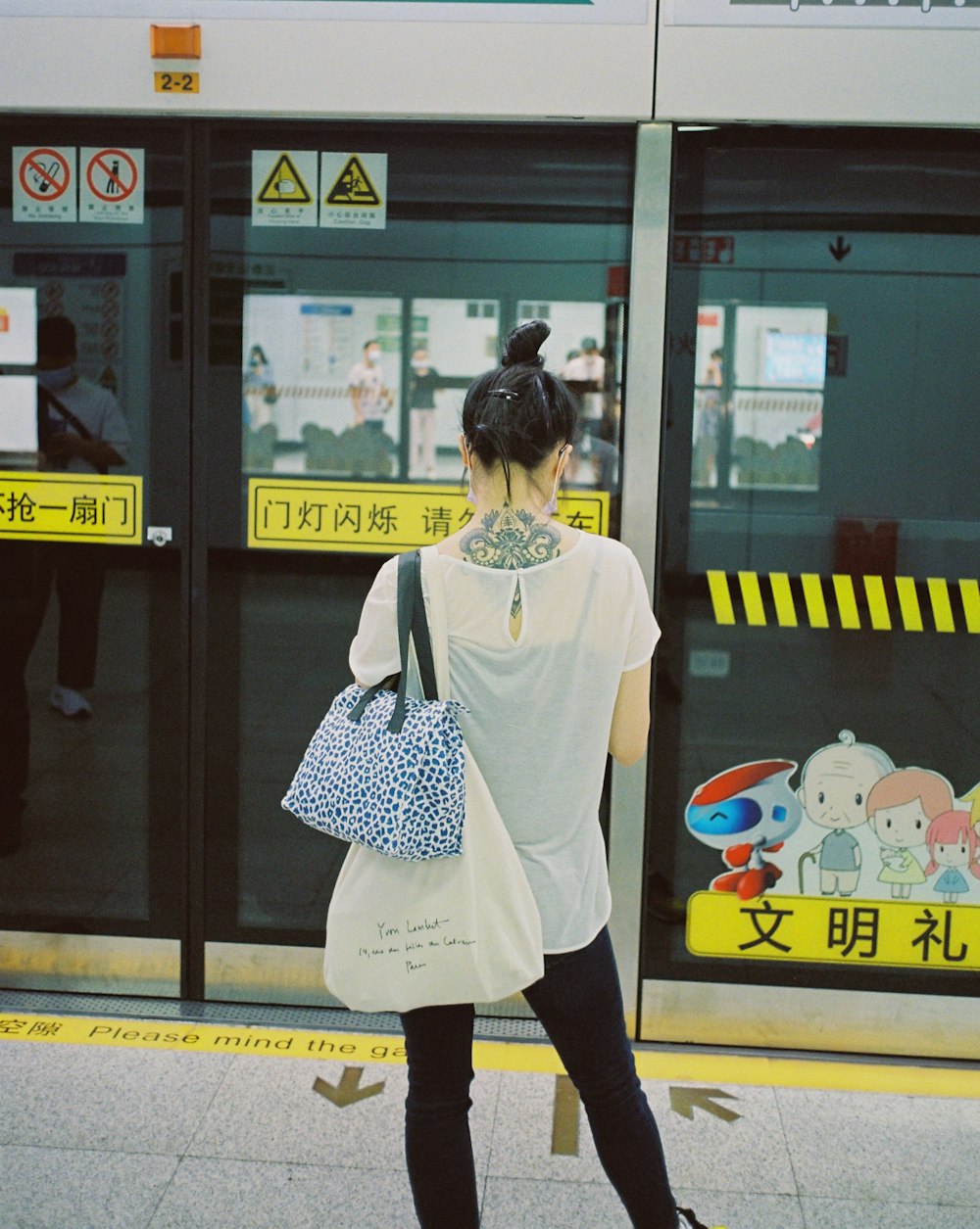 a woman with a tattoo on her neck walking past a train
