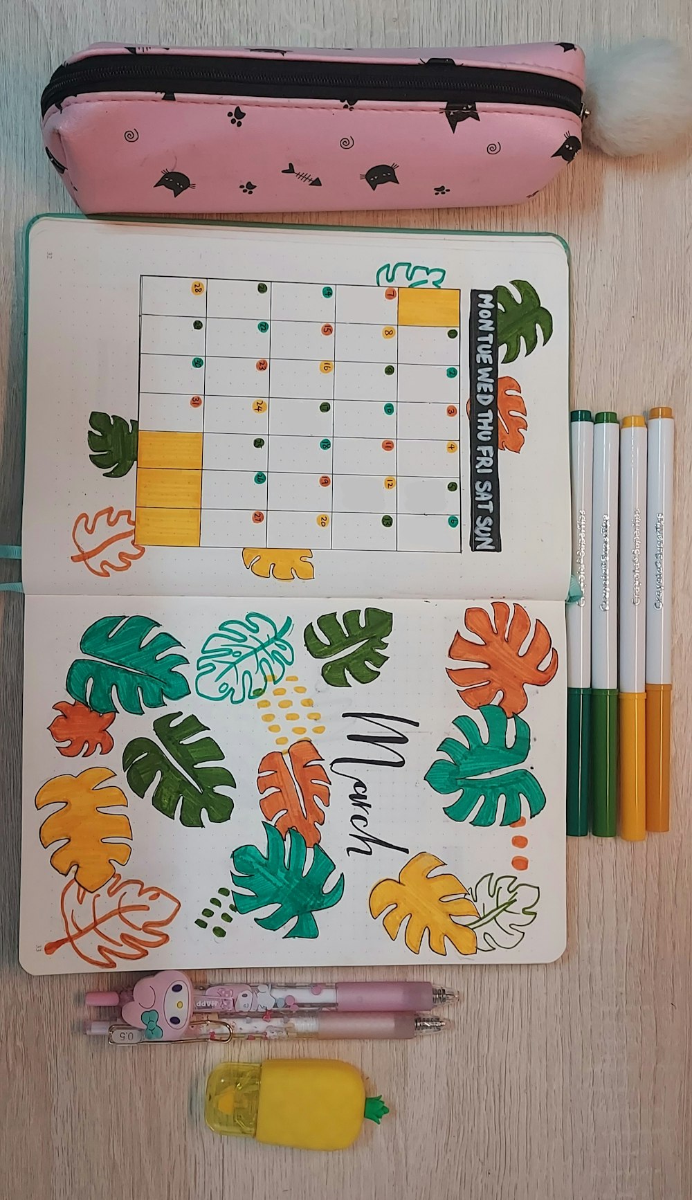 a planner, pens, and a pencil on a table