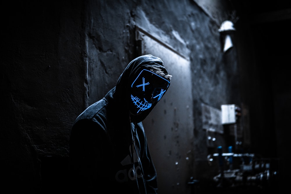 a man in a dark room wearing a neon mask
