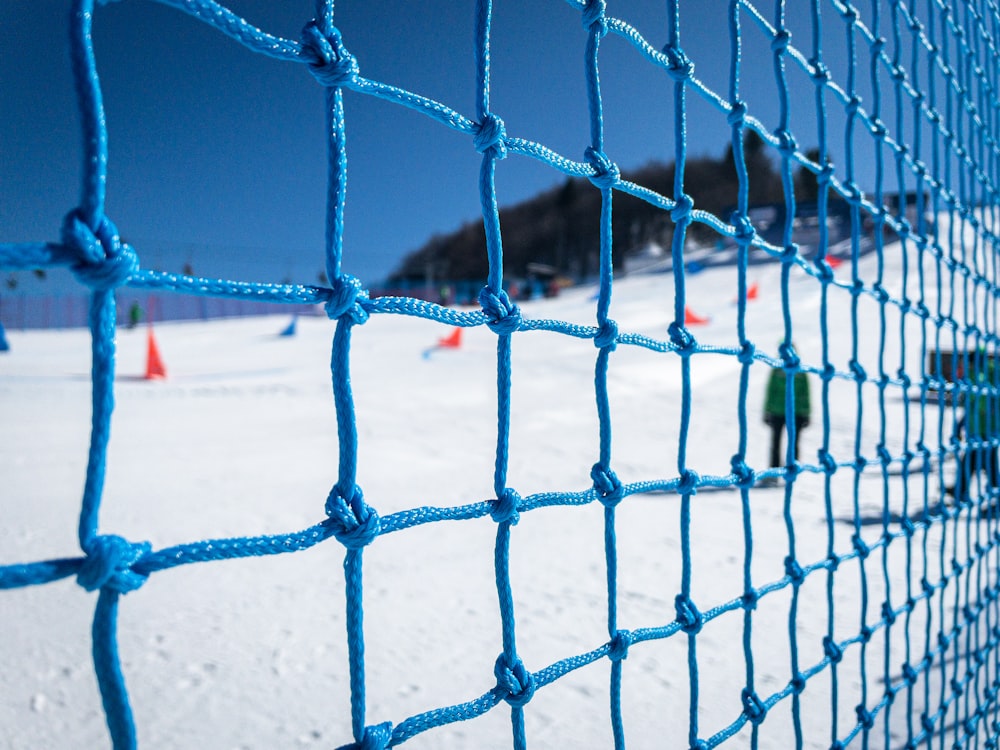 a blue net on the side of a snow covered ski slope