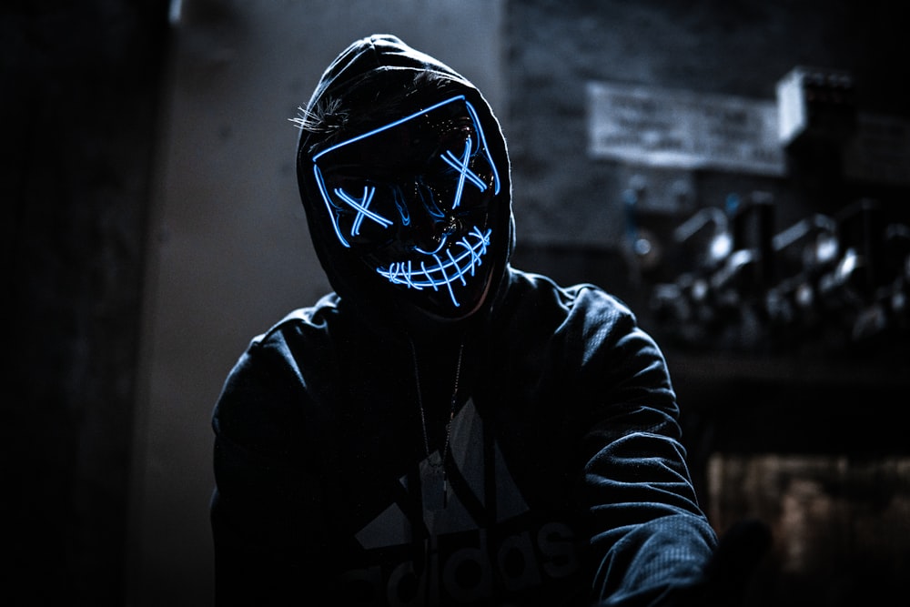a person wearing a neon mask in a dark room