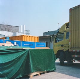 a yellow truck with a green tarp on the back of it
