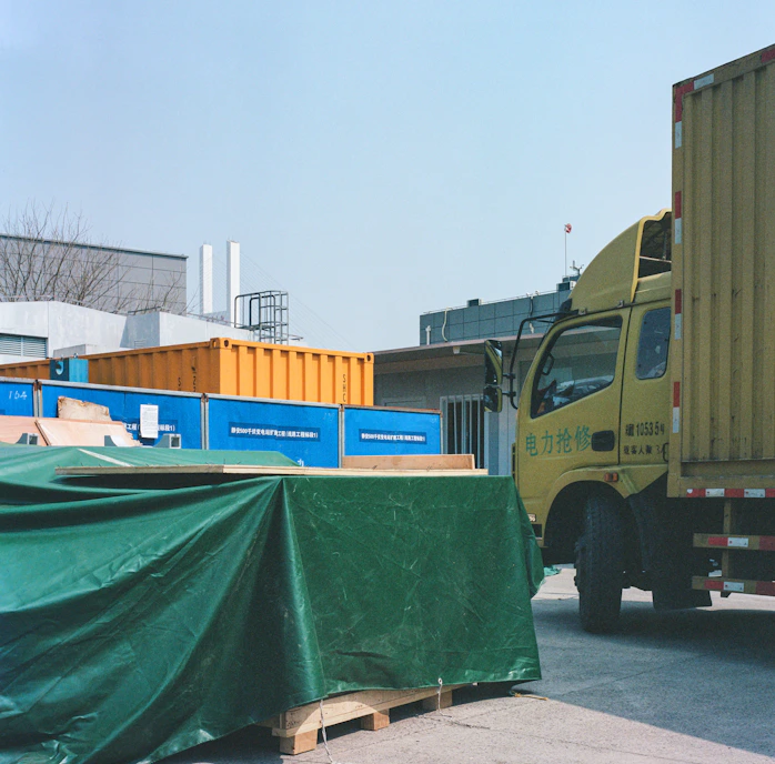 a yellow truck with a green tarp on the back of it