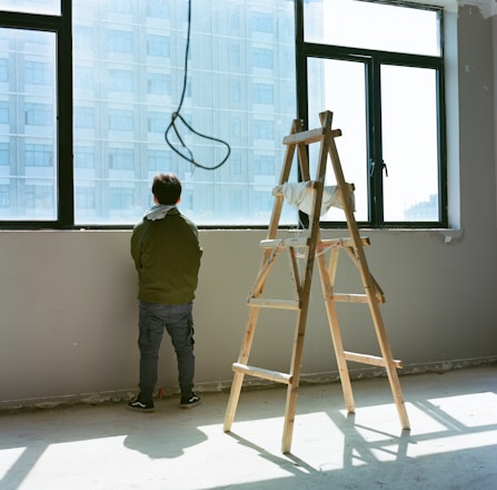 a man standing next to a ladder in front of a window