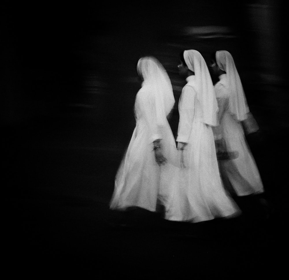 three women dressed in white walking down a street