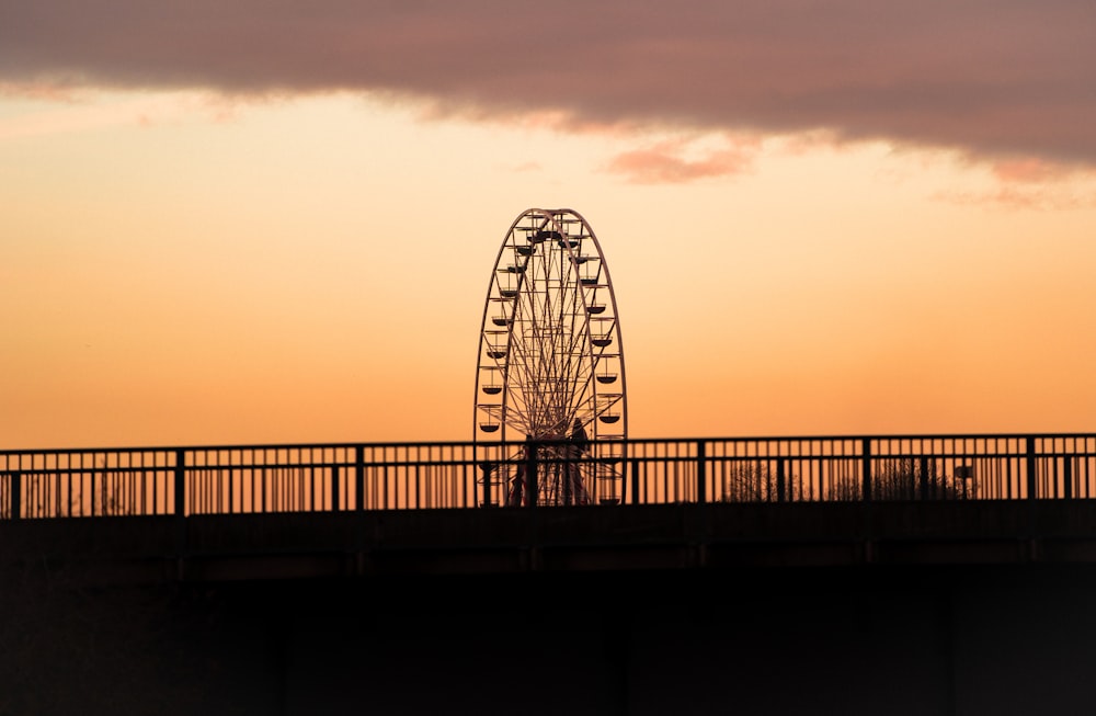 a ferris wheel sitting on top of a bridge