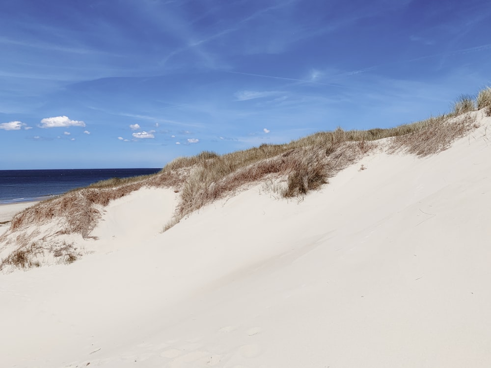 a sandy beach with a blue sky and ocean in the background