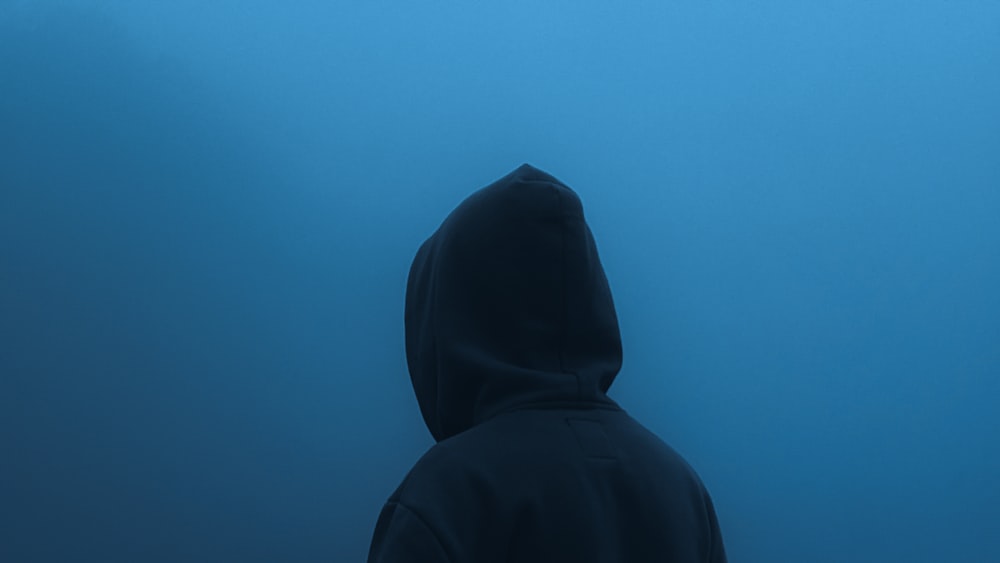 a person standing in the water wearing a hoodie