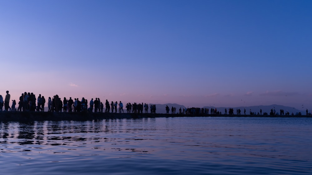 a group of people standing on the edge of a body of water