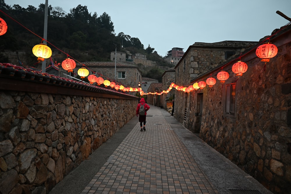 a woman walking down a street with lots of lanterns