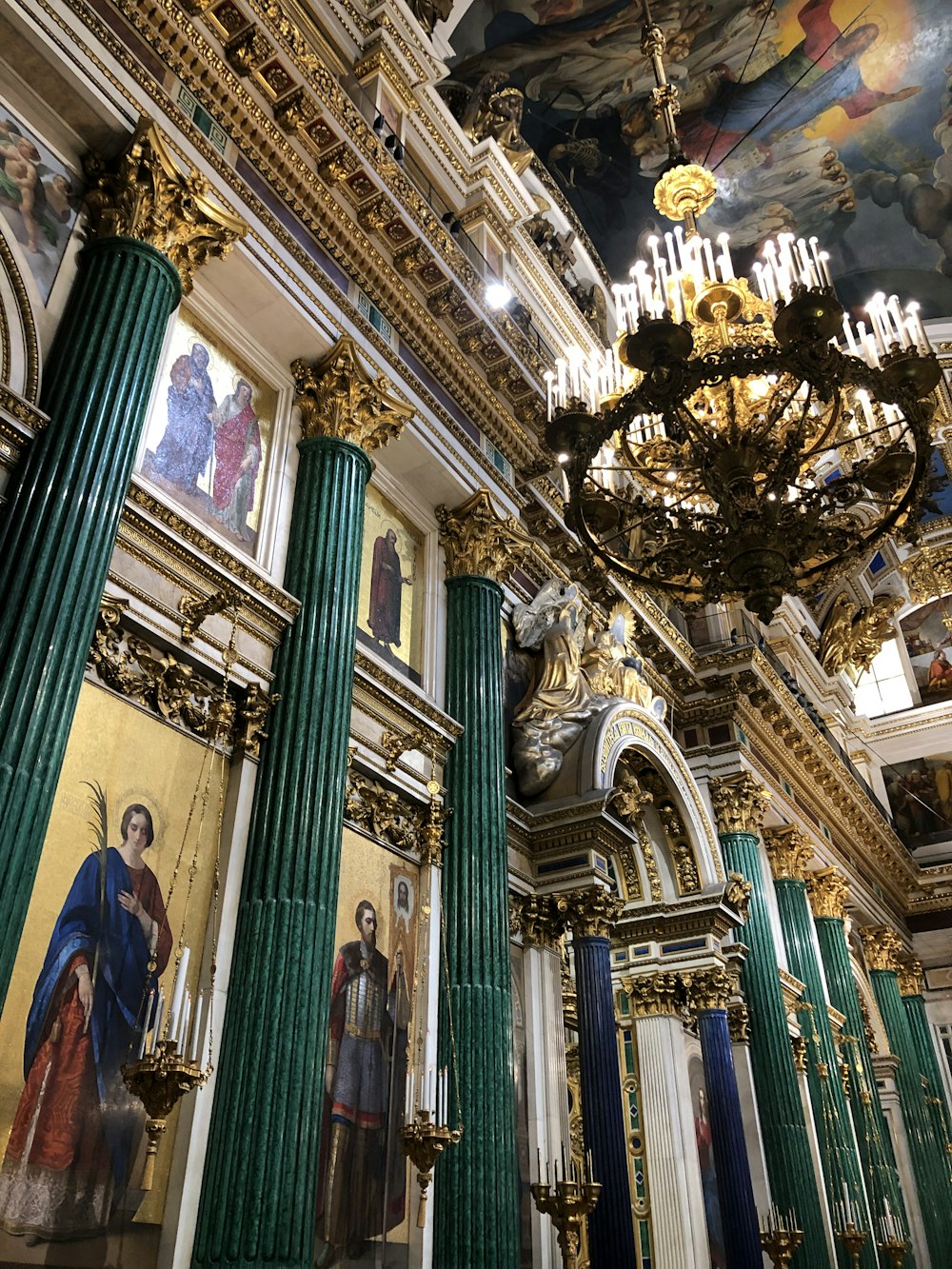 a church with a chandelier and paintings on the walls