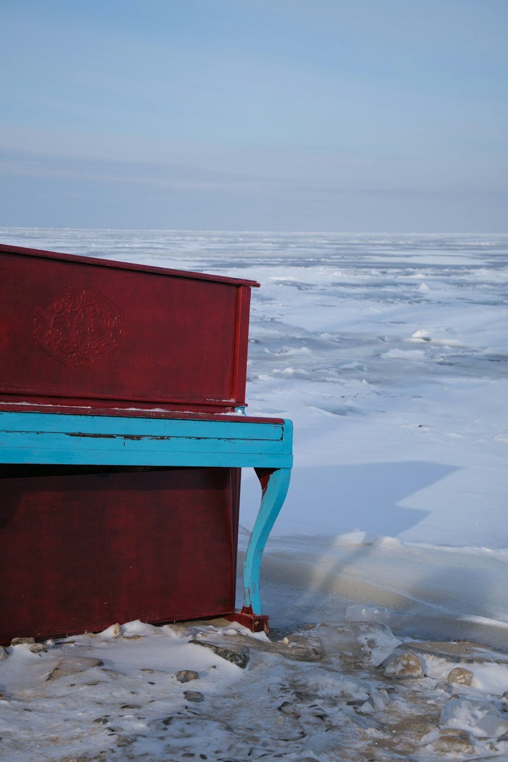 a blue and red bench sitting on top of snow covered ground