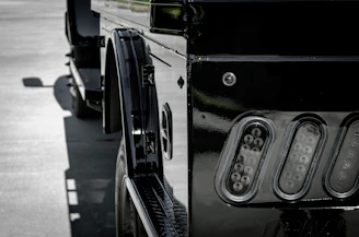 A shiny black pick-up truck with chrome details, showcased on a glossy floor with ambient lighting.