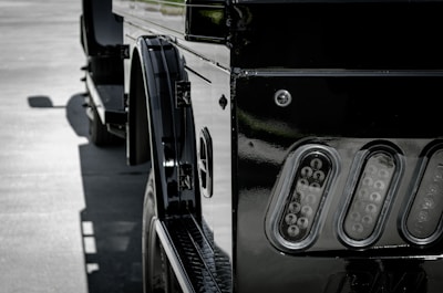 Close-up of a shiny SUV being carefully loaded onto a car carrier at a busy terminal.