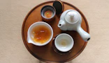 Close-up of a welcome tray with local snacks and a pot of tea on a bedside table.